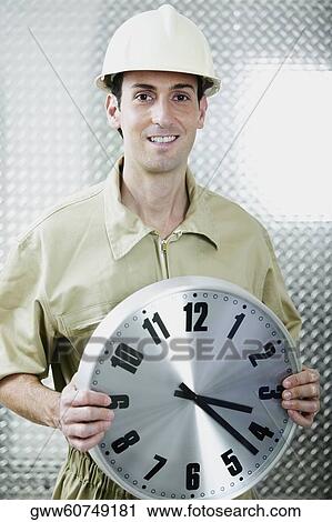 Portrait of a mid adult man holding a clock View Large Photo Image Stock Image - Portrait of a mid adult man holding a clock. Fotosearch