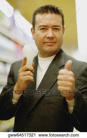 Portrait of a mid adult man holding a light bulb and showing a thumbs up sign View Large Photo Image Stock Image - Portrait of a mid adult man holding a light bulb and showing a thumbs up sign. Fotosearch