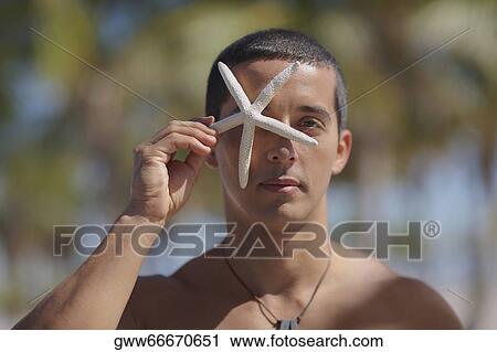 Portrait of a mid adult man holding a starfish in front of his face View Large Photo Image Stock Image - Portrait of a mid adult man holding a starfish in front of his face. Fotosearch