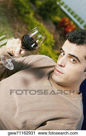 Portrait of a mid adult man holding a glass of red wine View Large Photo Image Stock Image - Portrait of a mid adult man holding a glass of red wine. Fotosearch