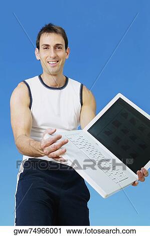Portrait of a mid adult man holding a laptop and smiling View Large Photo Image Stock Image - Portrait of a mid adult man holding a laptop and smiling. Fotosearch