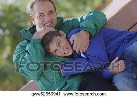 Portrait of a mid adult man hugging his son View Large Photo Image Stock Image - Portrait of a mid adult man hugging his son. Fotosearch