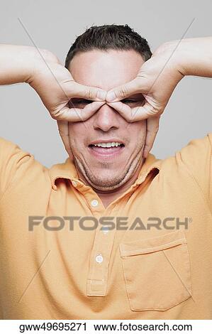 Stock Image - Portrait of a mid adult man pretending to wear glasses. Fotosearch