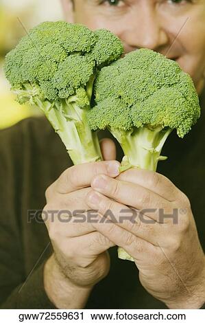 Portrait of a mid adult man showing two broccolis View Large Photo Image Stock Image - Portrait of a mid adult man showing two broccolis. Fotosearch