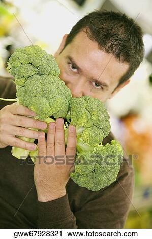 Portrait of a mid adult man smelling broccolis View Large Photo Image Stock Image - Portrait of a mid adult man smelling broccolis. Fotosearch