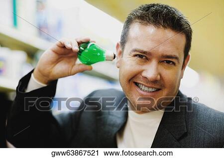 Portrait of a mid adult man smiling and holding a light bulb View Large Photo Image Stock Image - Portrait of a mid adult man smiling and holding a light bulb. Fotosearch