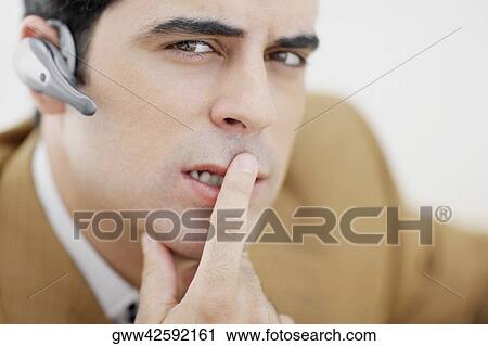 Stock Image - Portrait of a mid adult man thinking with finger on his lips. Fotosearch