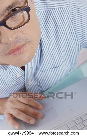 Stock Image - Portrait of a mid adult man working on a laptop. Fotosearch