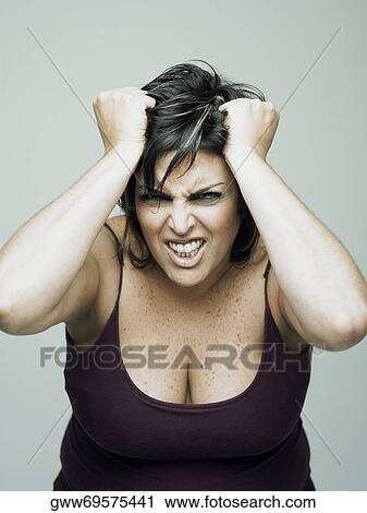 Stock Image - Portrait of a mid adult woman with her hand in her hair. Fotosearch