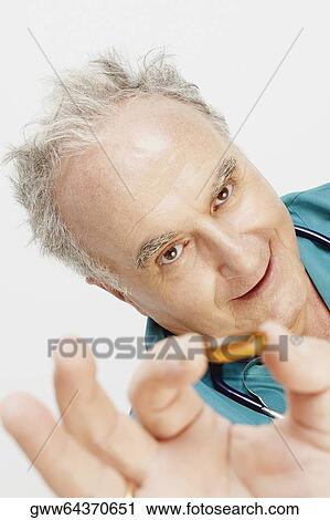 Portrait of a senior male doctor showing a capsule View Large Photo Image Stock Image - Portrait of a senior male doctor showing a capsule. Fotosearch