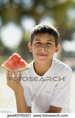 Portrait of a teenage boy holding a slice of watermelon View Large Photo Image Stock Image - Portrait of a teenage boy holding a slice of watermelon. Fotosearch
