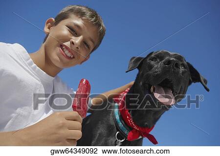 Portrait of a teenage boy holding ice-cream with a dog View Large Photo Image Stock Image - Portrait of a teenage boy holding ice-cream with a dog. Fotosearch