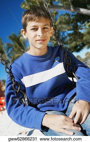 Portrait of a teenage boy sitting on a swing View Large Photo Image Stock Image - Portrait of a teenage boy sitting on a swing. Fotosearch