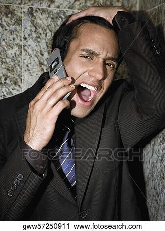 Stock Image - Portrait of a young businessman shouting into a mobile phone. Fotosearch