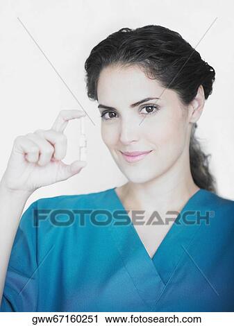 Stock Image - Portrait of a young female doctor holding a vial. Fotosearch