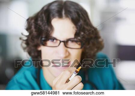 Portrait of a young male doctor holding an injection View Large Photo Image Stock Image - Portrait of a young male doctor holding an injection. Fotosearch