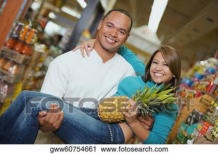 Portrait of a young man carrying a young woman in a supermarket View Large Photo Image Stock Image - Portrait of a young man carrying a young woman in a supermarket. Fotosearch