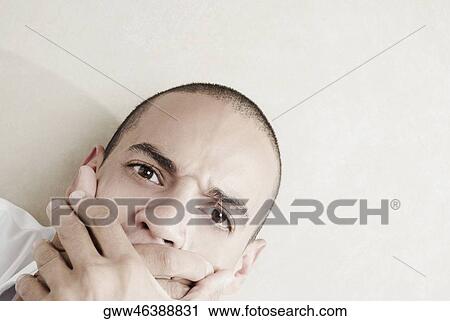 Portrait of a young man covering his mouth with his hands View Large Photo Image Stock Image - Portrait of a young man covering his mouth with his hands. Fotosearch
