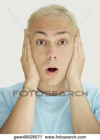 Stock Image - Portrait of a young man covering his ears with his hands. Fotosearch