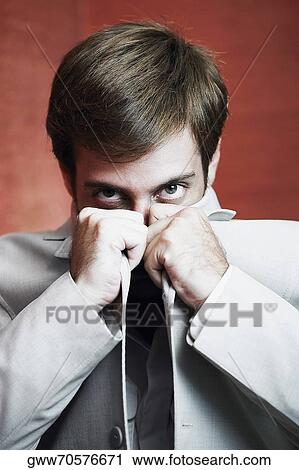 Portrait of a young man covering his face with his coat View Large Photo Image Stock Image - Portrait of a young man covering his face with his coat. Fotosearch