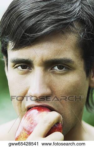 Portrait of a young man eating an apple View Large Photo Image Stock Image - Portrait of a young man eating an apple. Fotosearch