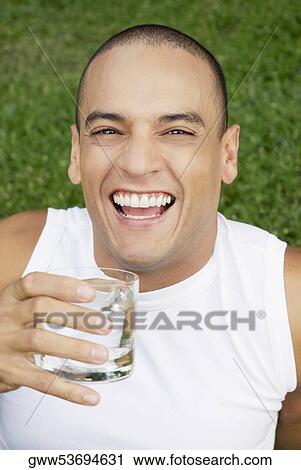 Portrait of a young man holding a glass of water and smiling View Large Photo Image Stock Image - Portrait of a young man holding a glass of water and smiling. Fotosearch