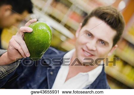 Portrait of a young man holding a papaya in a supermarket View Large Photo Image Stock Image - Portrait of a young man holding a papaya in a supermarket. Fotosearch