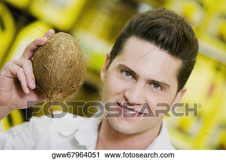 Portrait of a young man holding a coconut View Large Photo Image Stock Image - Portrait of a young man holding a coconut. Fotosearch