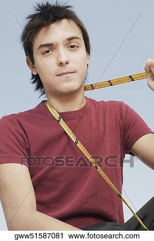Portrait of a young man holding a tape measure around his neck View Large Photo Image Stock Image - Portrait of a young man holding a tape measure around his neck. Fotosearch