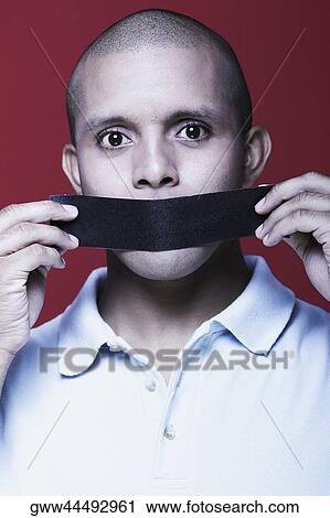 Portrait of a young man holding duct tape in front of his mouth View Large Photo Image Stock Image - Portrait of a young man holding duct tape in front of his mouth. Fotosearch