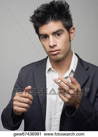 Portrait of a young man holding cigarette and a cigarette lighter View Large Photo Image Stock Image - Portrait of a young man holding cigarette and a cigarette lighter. Fotosearch