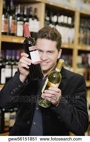 Portrait of a young man holding two wine bottles in a liquor store View Large Photo Image Stock Image - Portrait of a young man holding two wine bottles in a liquor store. Fotosearch