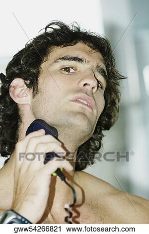 Portrait of a young man shaving with an electric razor View Large Photo Image Stock Image - Portrait of a young man shaving with an electric razor. Fotosearch