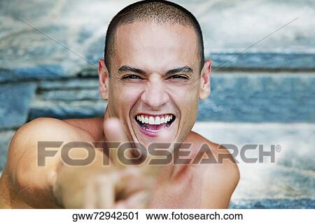 Stock Image - Portrait of a young man showing a peace sign. Fotosearch
