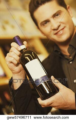 Portrait of a young man showing a wine bottle in a liquor store View Large Photo Image Stock Image - Portrait of a young man showing a wine bottle in a liquor store. Fotosearch