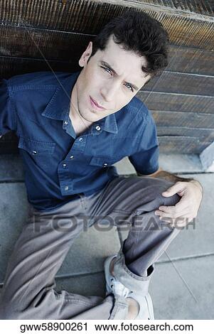 Portrait of a young man sitting with his hands on his knees View Large Photo Image Stock Image - Portrait of a young man sitting with his hands on his knees. Fotosearch