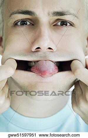 Portrait of a young man stretching his mouth and sticking his tongue out View Large Photo Image Stock Image - Portrait of a young man stretching his mouth and sticking his tongue out. Fotosearch
