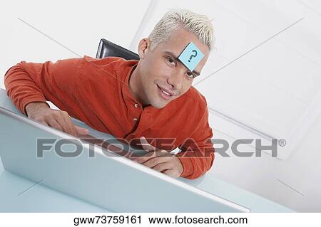 Portrait of a young man using a laptop with an adhesive note on his forehead View Large Photo Image Stock Image - Portrait of a young man using a laptop with an adhesive note on his forehead. Fotosearch