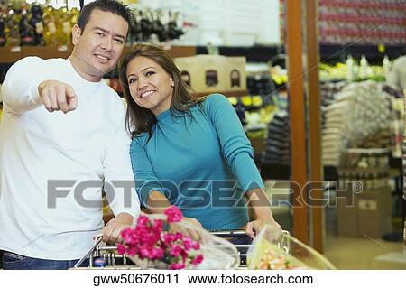 Portrait of a young woman and a mid adult man standing in a supermarket and smiling View Large Photo Image Stock Image - Portrait of a young woman and a mid adult man standing in a supermarket and smiling. Fotosearch