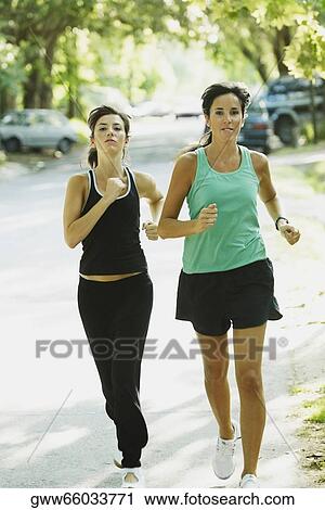Portrait of a young woman and a mid adult woman jogging on the road View Large Photo Image Stock Image - Portrait of a young woman and a mid adult woman jogging on the road. Fotosearch