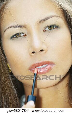 Portrait of a young woman applying lip liner View Large Photo Image Stock Image - Portrait of a young woman applying lip liner. Fotosearch