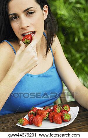 Portrait of a young woman eating a strawberry View Large Photo Image Stock Image - Portrait of a young woman eating a strawberry. Fotosearch