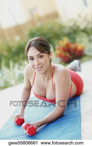 Stock Image - Portrait of a young woman exercising with dumbbells. Fotosearch
