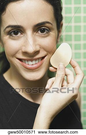 Portrait of a young woman holding a powder puff and smiling View Large Photo Image Stock Image - Portrait of a young woman holding a powder puff and smiling. Fotosearch