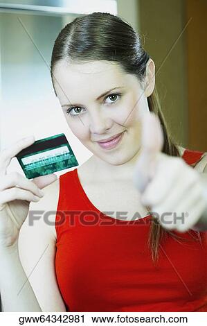 Stock Image - Portrait of a young woman holding a credit card. Fotosearch