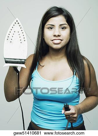 Stock Image - Portrait of a young woman holding an iron. Fotosearch