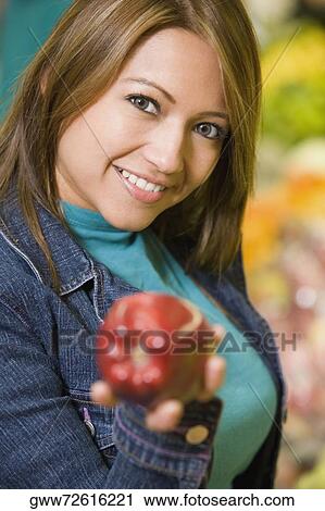 Portrait of a young woman holding an apple and smiling View Large Photo Image Stock Image - Portrait of a young woman holding an apple and smiling. Fotosearch
