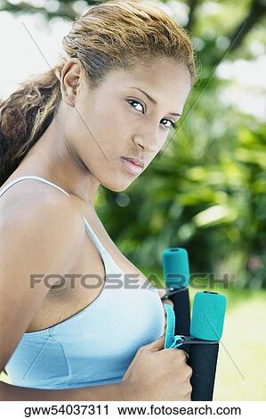 Portrait of a young woman holding dumbbells View Large Photo Image Stock Image - Portrait of a young woman holding dumbbells. Fotosearch