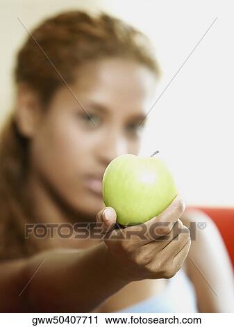 Portrait of a young woman showing an apple View Large Photo Image Stock Image - Portrait of a young woman showing an apple. Fotosearch