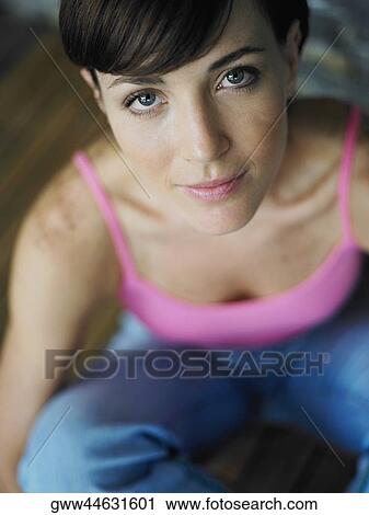 Stock Image - Portrait of a young woman sitting on a hardwood floor. Fotosearch